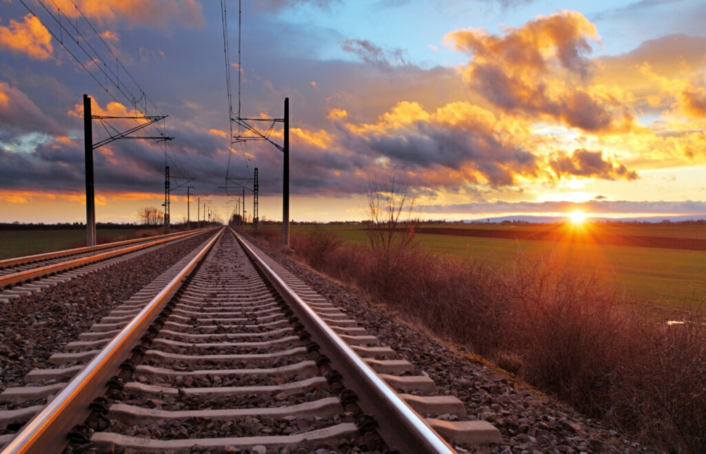 Railroad tracks in foreground with sunset in the distance