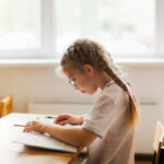 Schoolgirl reading a book at a desk in a classroom