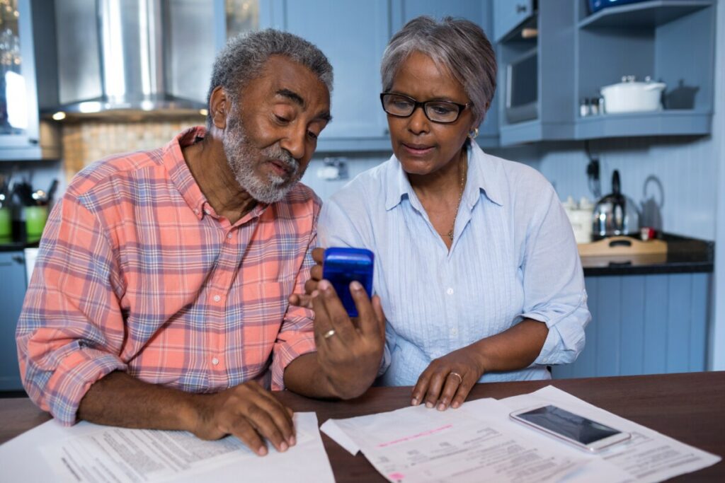 Couple sitting at a table with papers looking at a calculator together.