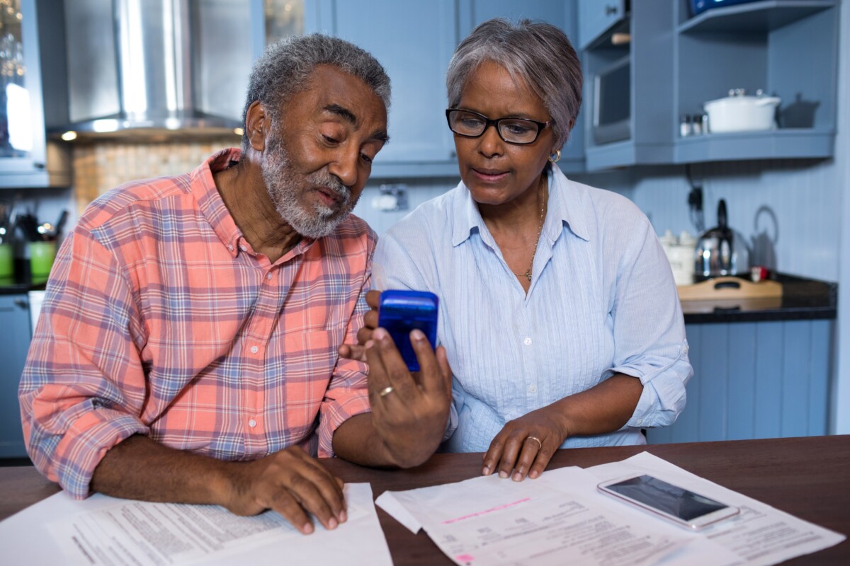 Couple sitting at a table with papers looking at a calculator together.