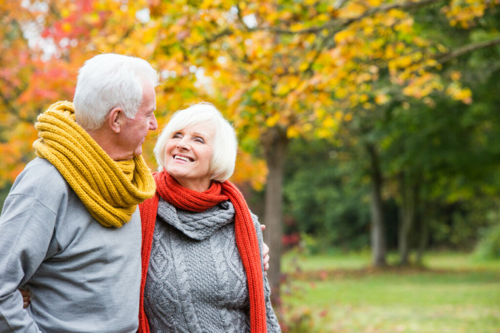 Retirement age couple walking through park.