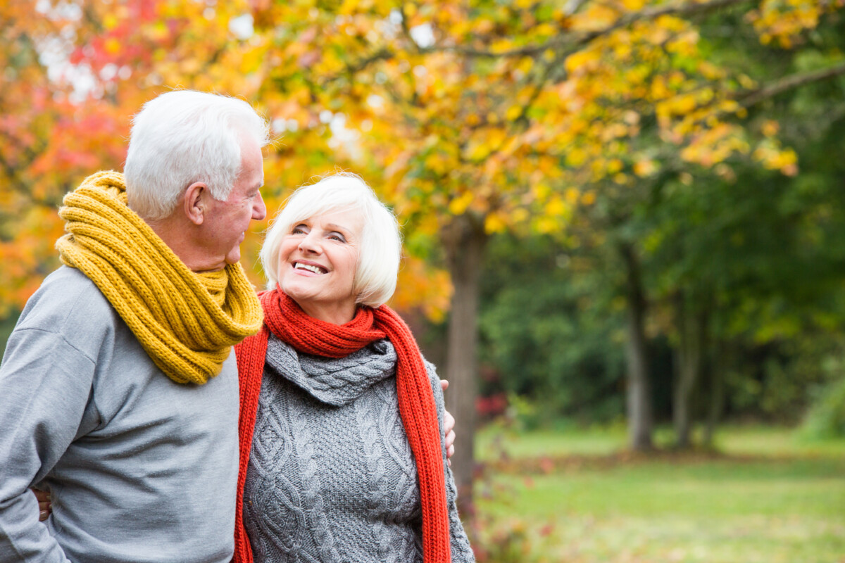 Retirement age couple walking through park.
