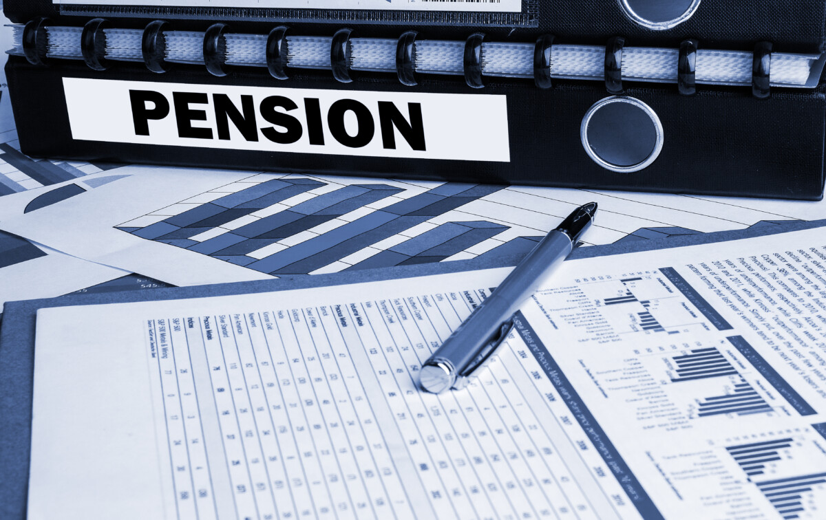 Charts on a paper with a pen and a binder labeled "PENSION"