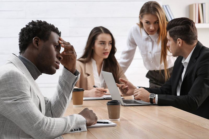 image of distraught african-american man at work table seemingly experiencing racial discrimination