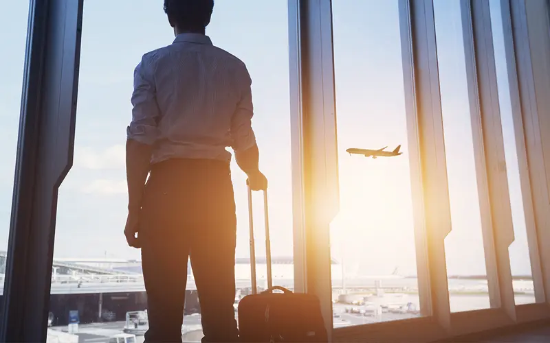 image of business traveler at airport watching plane take off at sunset