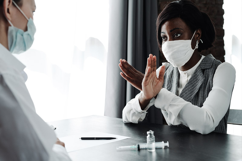 image of woman holding up her arms in an x to refuse a vaccine