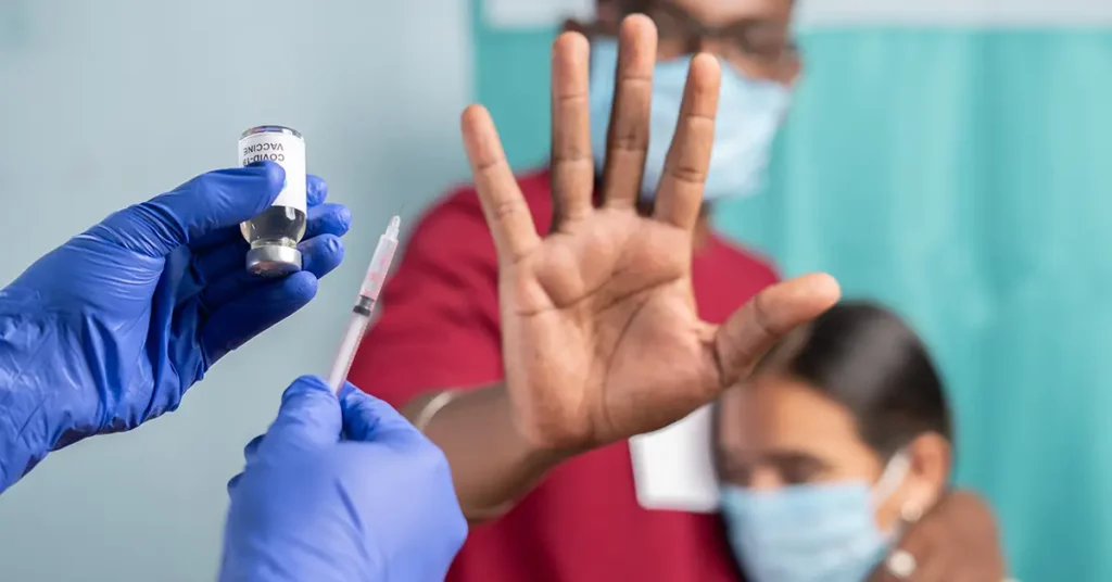 image of man and wife holding hand up rejecting a vaccine