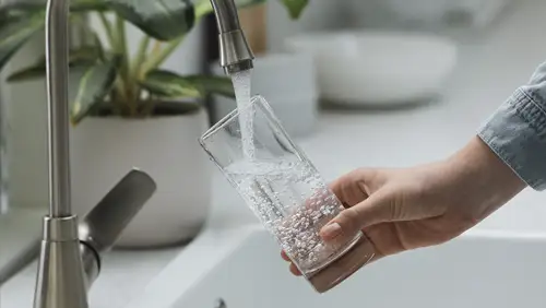 hand holding glass getting tapwater from sink