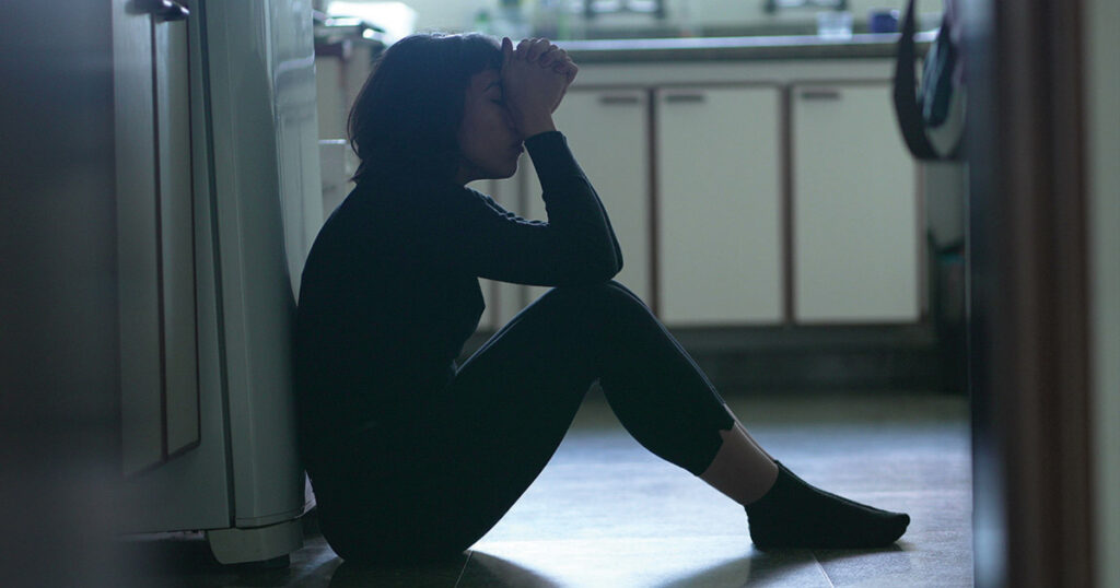image of woman upset sitting on kitchen floor