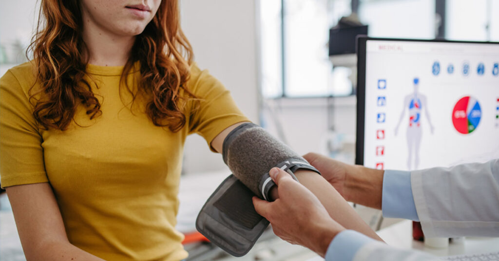 image of young woman at doctor's office with nurse taking blood pressure