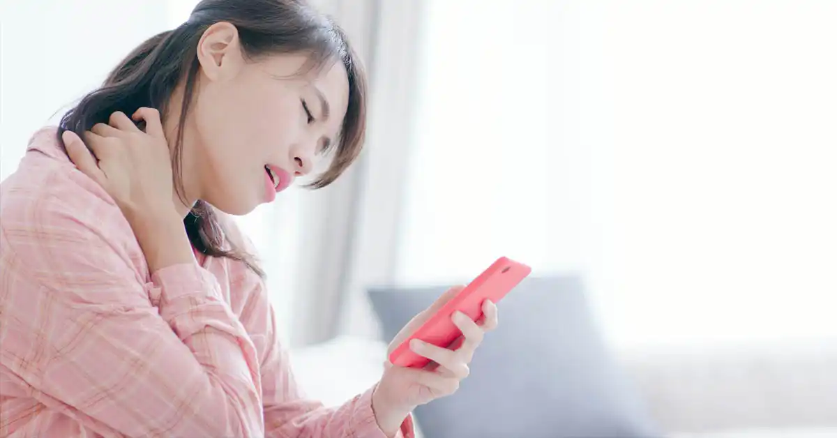 image of a woman holding her neck in pain while dialing her phone, representing when to contact a vaccine injury lawyer