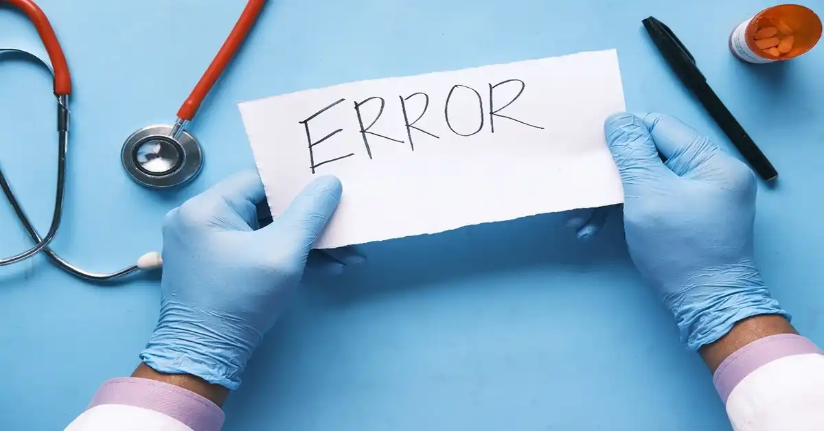 image of a doctor's hands in gloves holding a note that reads error, representing misdiagnosis