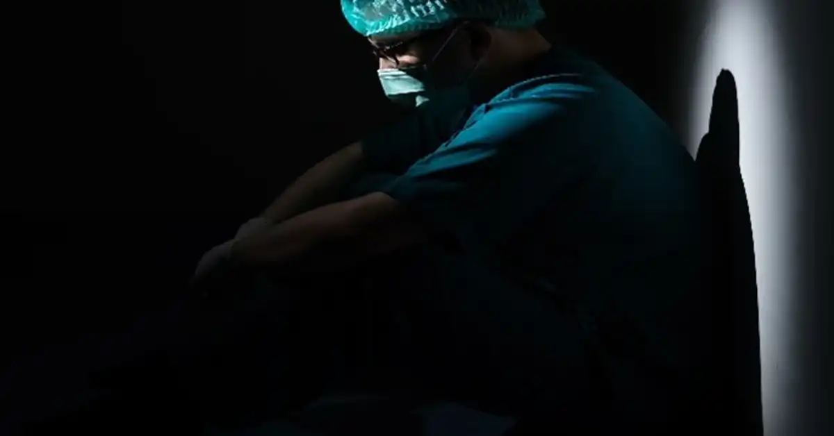 image of a surgeon in a dark room sitting on the floor representing surgery injury