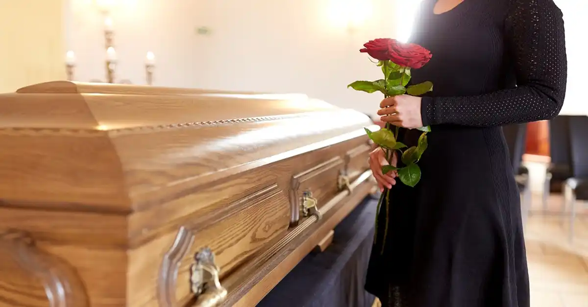 image of a woman in black dress holding flowers by a casket representing wrongful death