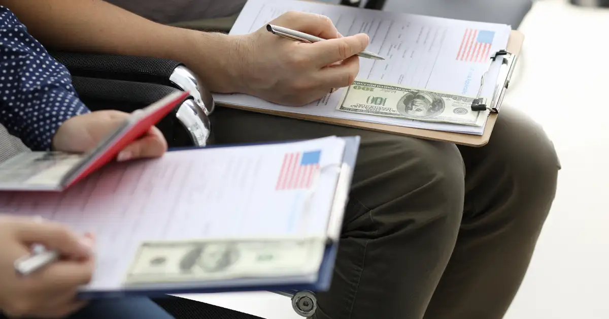image of people filling out immigration paper work on clipboards with money, representing USCIS fee changes