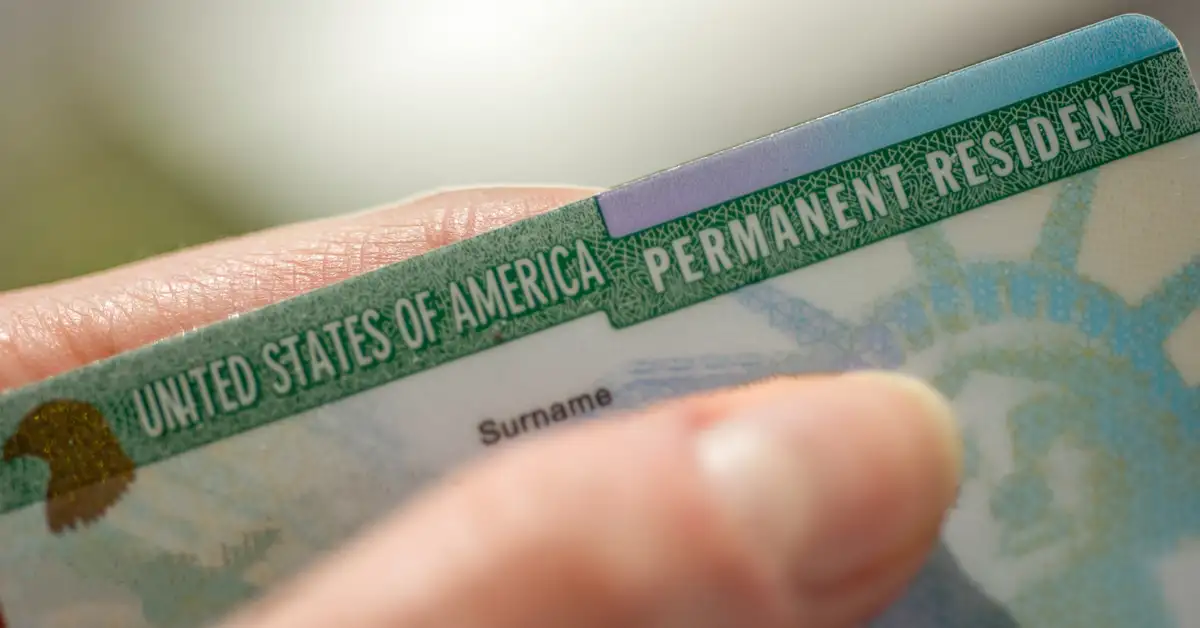 close up image of a hand holding a united states permanent resident card, or green card, representing green card rights