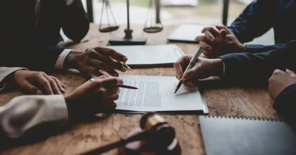 In a professional office setting, a group of lawyers is intently reviewing medical documents related to vaccine injury claims, focusing on cases involving flu vaccine-related injuries and potential compensation under the national vaccine injury compensation program. The atmosphere is serious as they prepare to present evidence for clients who may have experienced adverse reactions to flu shots.