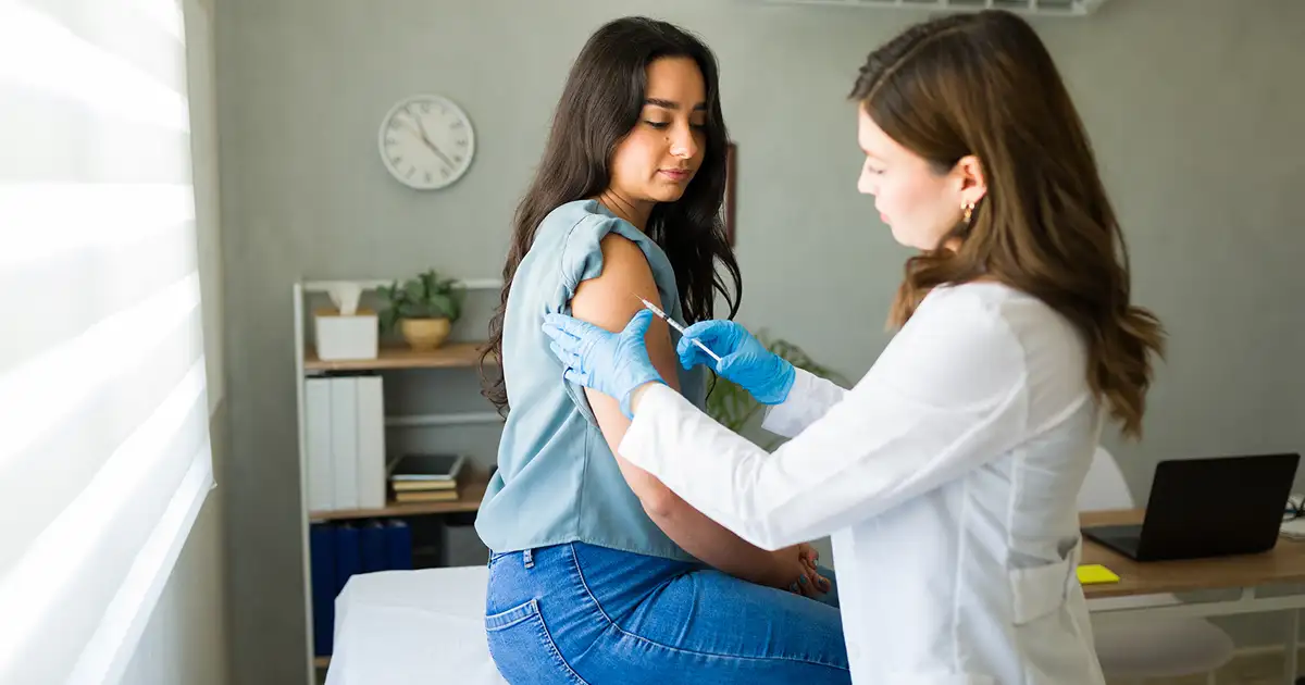 A medical professional is shown preparing a flu vaccine injection, holding a syringe filled with the seasonal influenza vaccine. The setting emphasizes the importance of flu shots in disease control and highlights the potential need for vaccine injury compensation for rare adverse reactions.