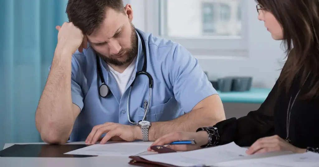 A doctor is seen in a medical consultation, reviewing patient charts alongside vaccine information, highlighting the importance of understanding vaccine-related injuries and the potential need for legal representation from experienced vaccine injury lawyers. The scene emphasizes the role of medical experts in addressing vaccine injury claims and the support available for those affected.