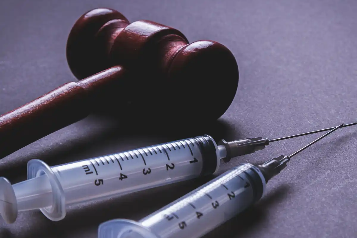 Close-up of syringes and a wooden gavel, representing medical law, vaccine injury cases, and the importance of hiring an experienced vaccine injury attorney to navigate compensation claims in the U.S. Court of Federal Claims.