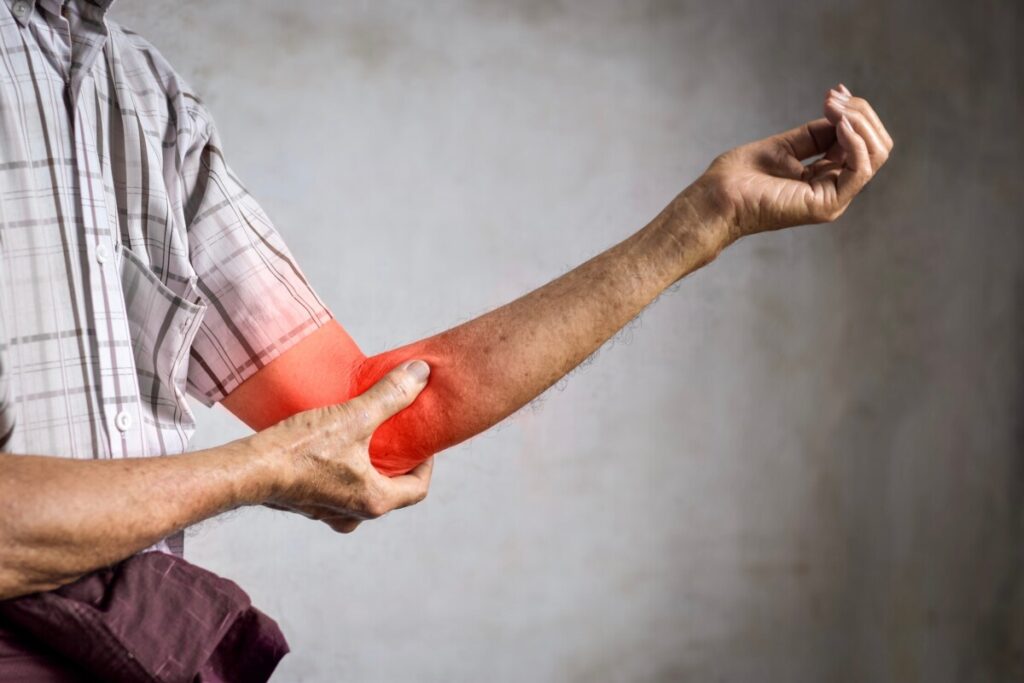 Older man gripping inflamed elbow, bursitis style pain after vaccine