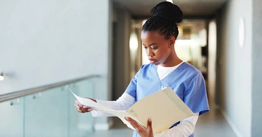 Healthcare professional reviewing medical records in a hospital hallway, illustrating documentation involved in vaccine injury cases