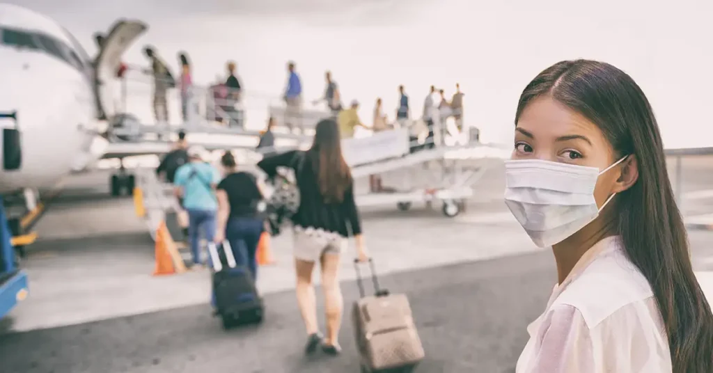 A traveler wearing a mask prepares to board an airplane, reflecting situations where immigration attorneys assist individuals navigating international travel requirements.