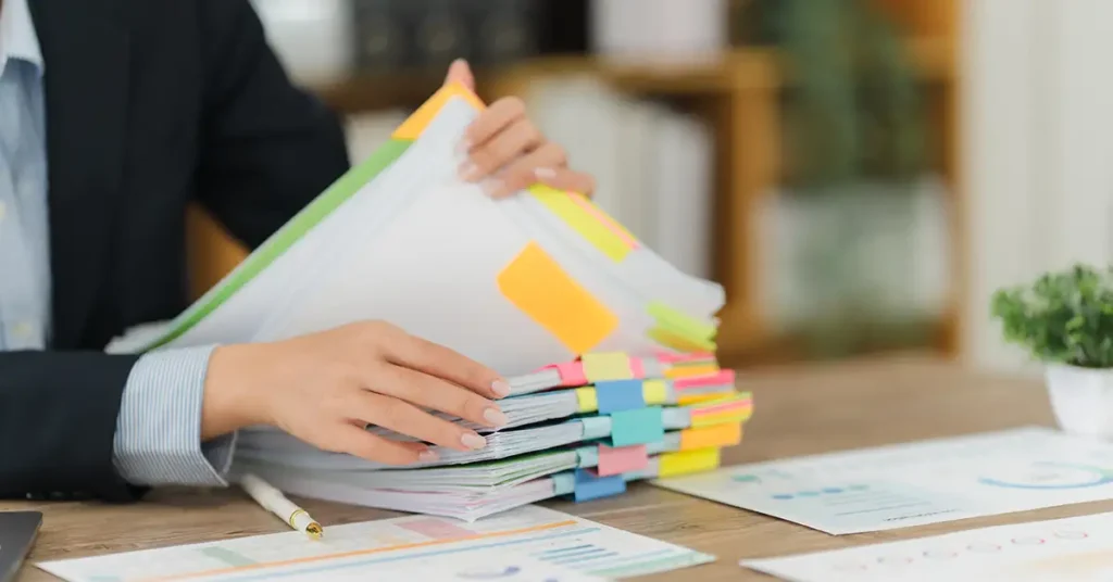Stack of legal and medical documents marked with tabs, illustrating the detailed records involved in vaccine injury cases