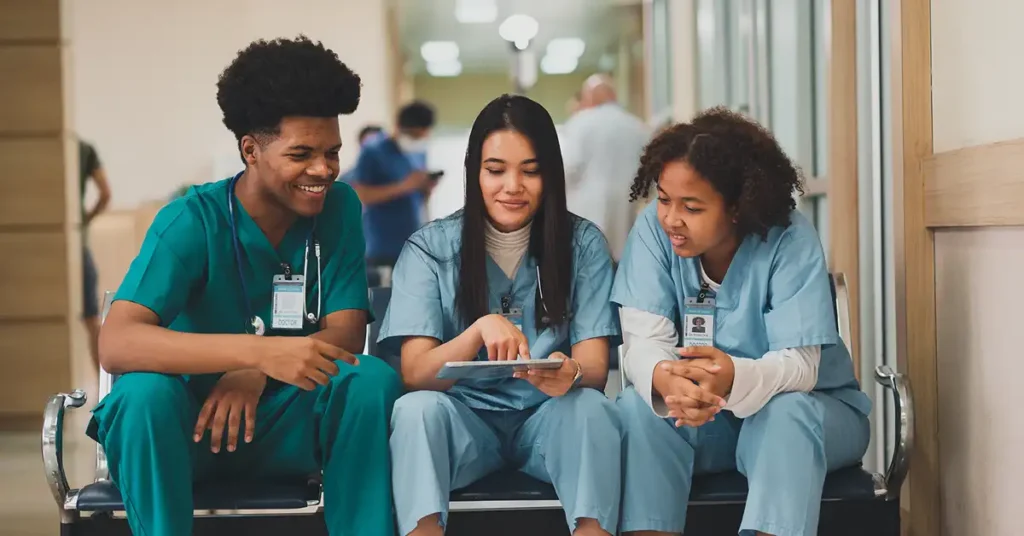 Nursing students in scrubs reviewing a tablet during clinical rotation, vaccine exemption legal help