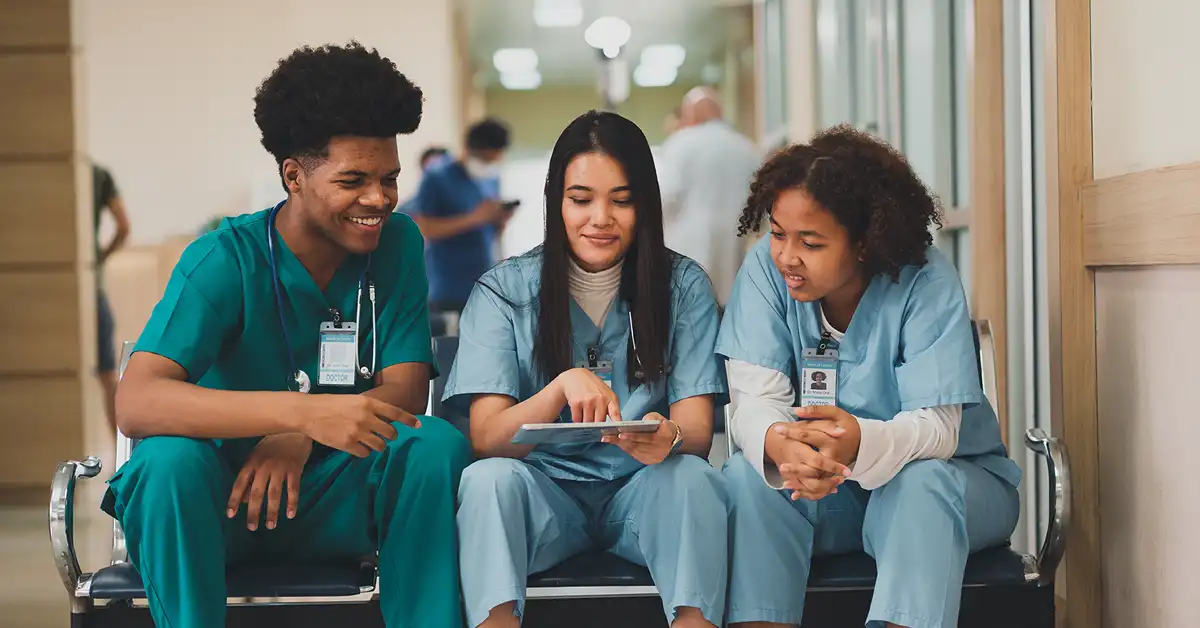 Nursing students in scrubs reviewing a tablet during clinical rotation, vaccine exemption legal help