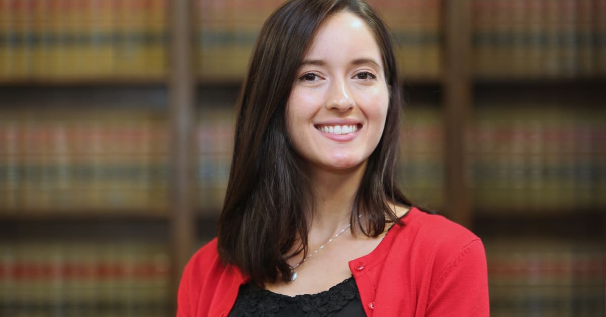 Female attorney standing in front of law books, representing legal representation for vaccine injury claims