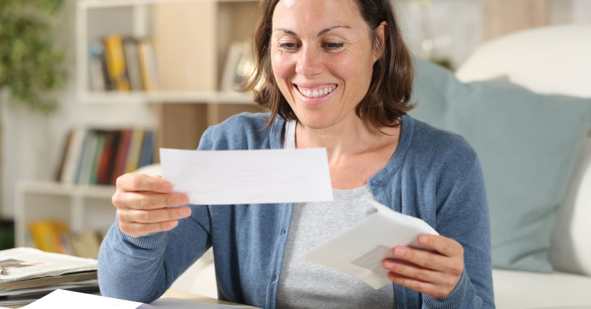 Woman reviewing paperwork at home, reflecting communication and compensation notices related to vaccine injury claims