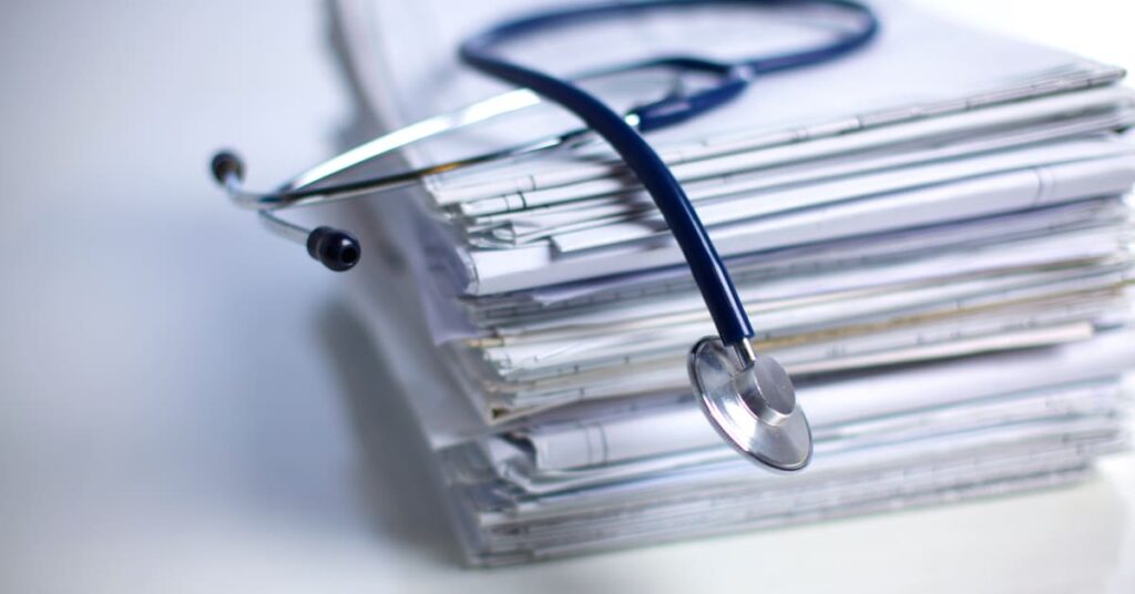 Stack of medical records with a stethoscope on top, reflecting the documentation required in vaccine injury cases