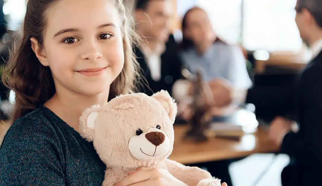 In the image, a family consisting of parents and their young child is sitting at a table with an immigration attorney, who is reviewing medical documents, including vaccination records and a medical examination report. The scene captures the importance of discussing vaccination requirements and potential vaccine waivers based on religious or moral convictions in the context of immigration services.