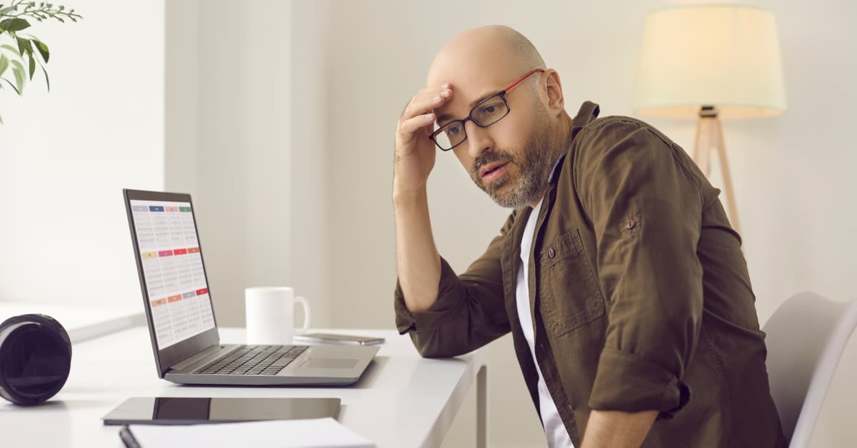 A man looking stressed at a desk beside a laptop, reflecting time-sensitive immigration matters managed by immigration attorneys.