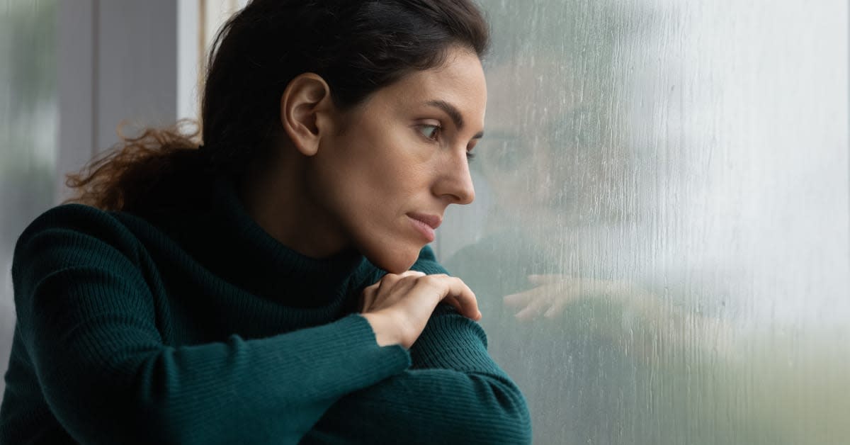 A woman looking out a rain-streaked window, reflecting personal immigration concerns addressed by immigration attorneys.