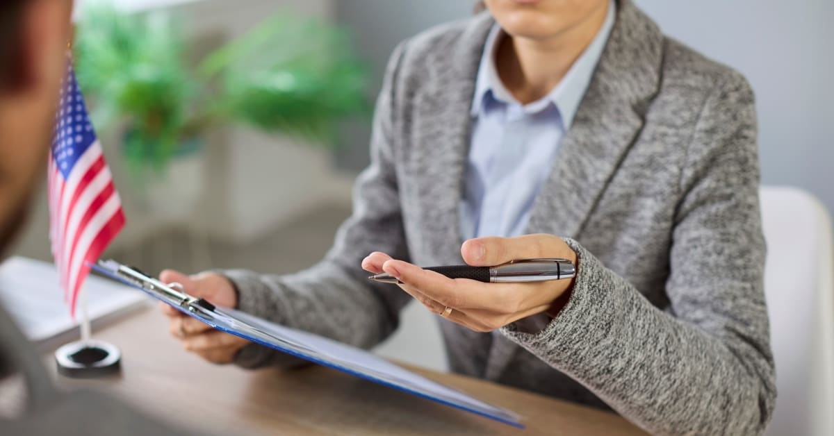 A person reviewing a form on a clipboard in an office setting, reflecting immigration interviews supported by immigration attorneys.