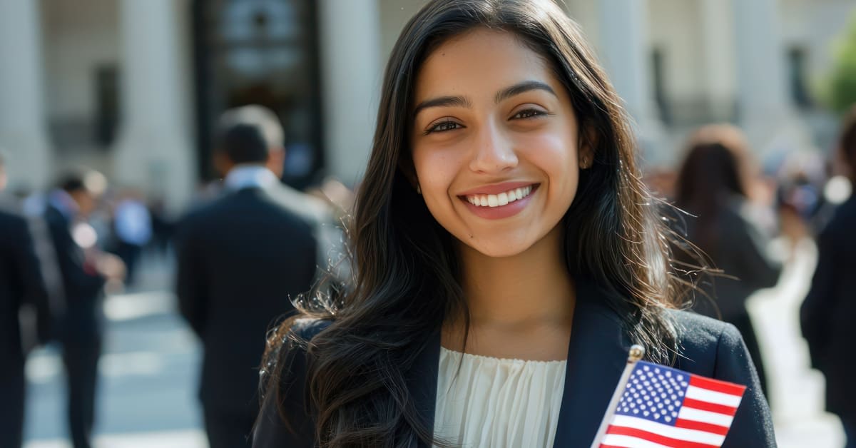 A woman smiling while holding a small U.S. flag, reflecting citizenship and immigration matters assisted by immigration attorneys.