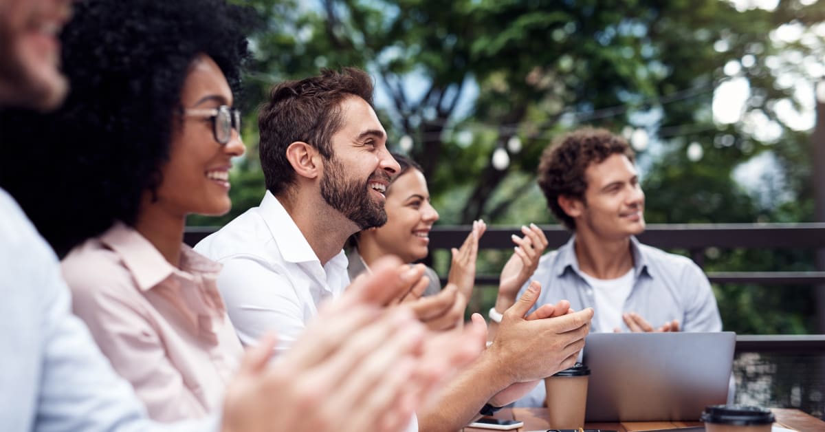 Professionals applauding during an outdoor business gathering, reflecting visitor visa activity questions addressed by immigration attorneys.