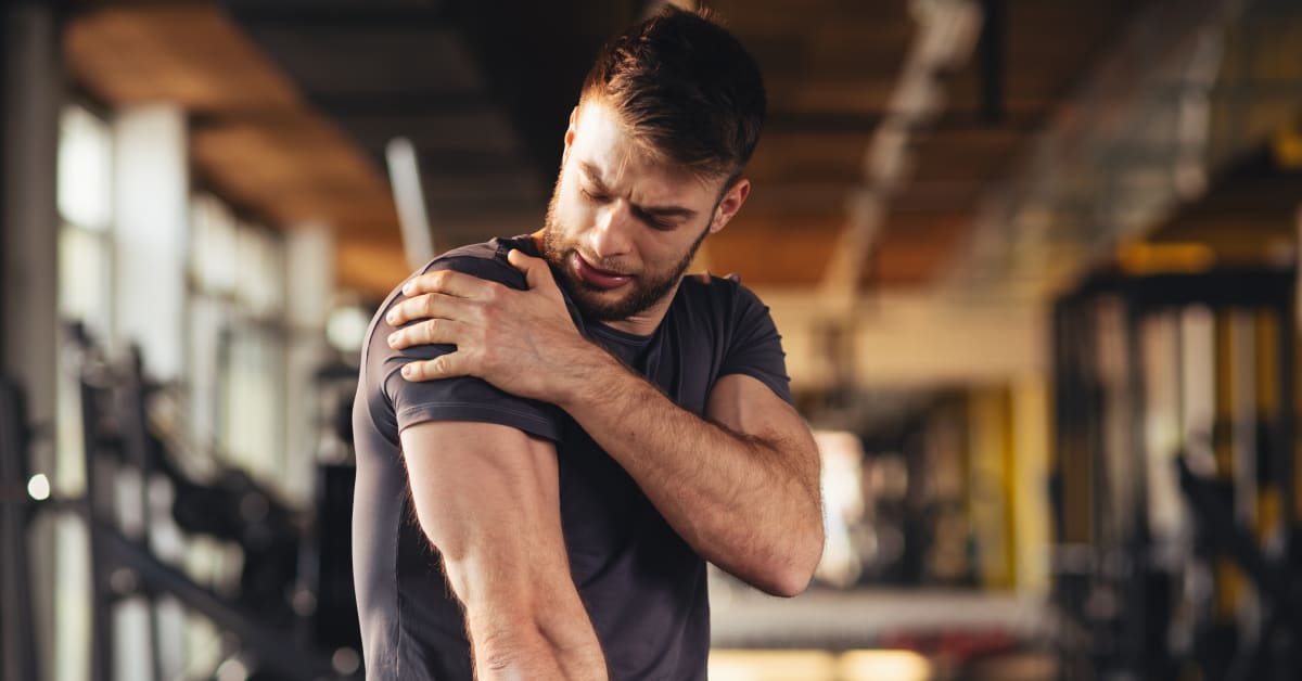 Man holding his shoulder in discomfort while exercising, illustrating persistent shoulder pain that may require medical evaluation following a vaccination
