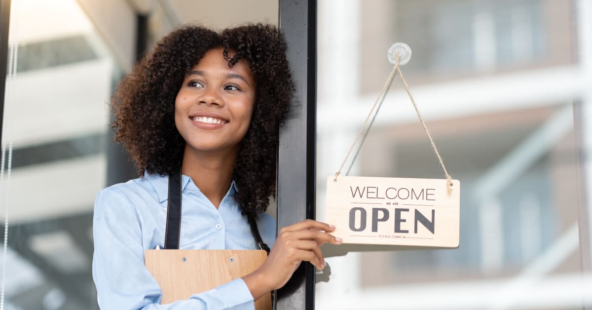 A business owner holding an open sign, representing investor and business immigration matters assisted by immigration attorneys.