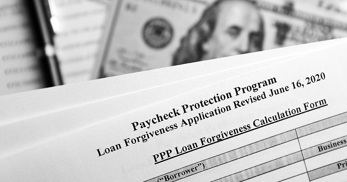 paycheck protection program paper in front of hundred dollar bills