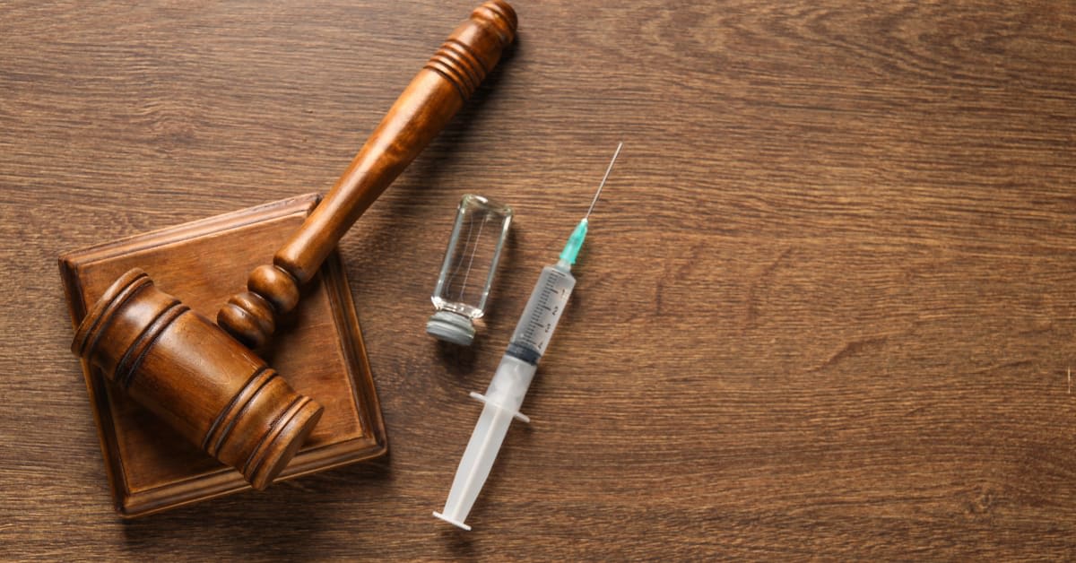 Judge’s gavel beside a medical vial and syringe, representing vaccination-related immigration issues handled by immigration attorneys.
