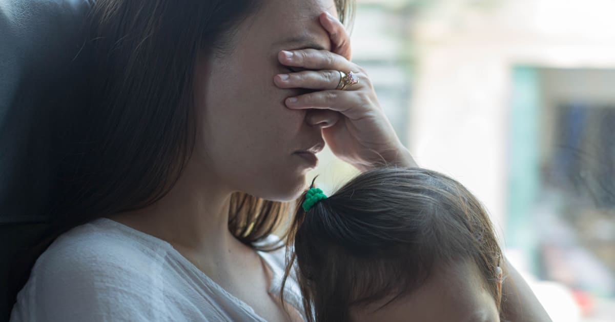 A distressed mother holding her child, reflecting the challenges of denied immigration vaccine waivers addressed by immigration attorneys.