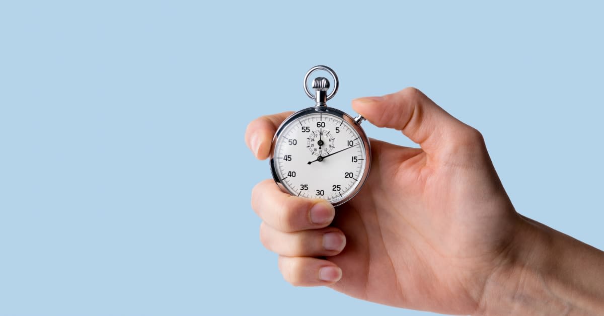 A hand holding a stopwatch against a blue background, representing immigration deadlines and time-sensitive applications managed by immigration attorneys.